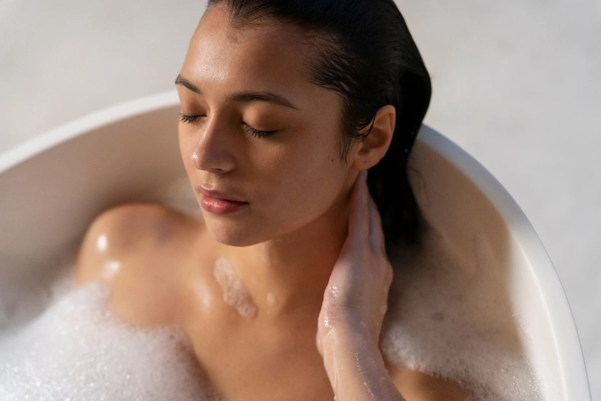 Relaxed woman in a warm bath, representing a daily underarm cleansing routine with antibacterial soap for odor control.