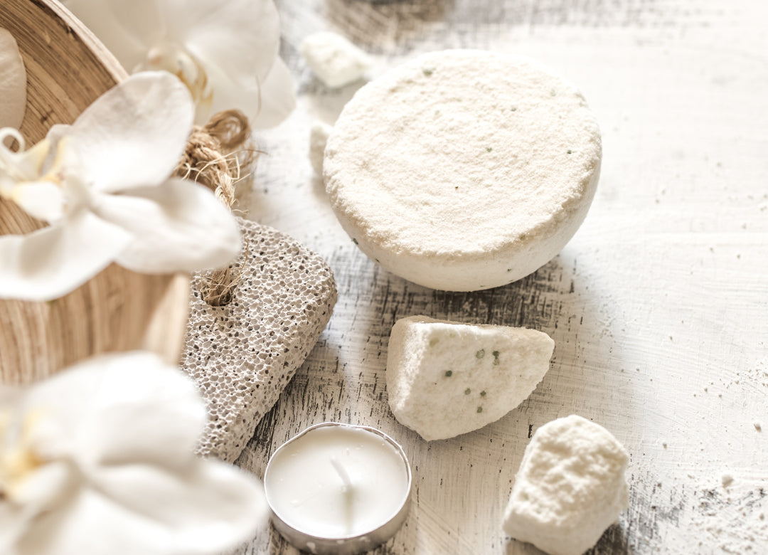 Flat lay of natural skincare elements with solid soap, white orchids and candles - evoking a clean, soothing ritual in the Soaporize contact section